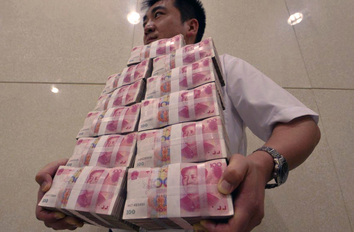 Сотрудник китайской фирмы несет пачки банкнот достоинством в 100 юаней.